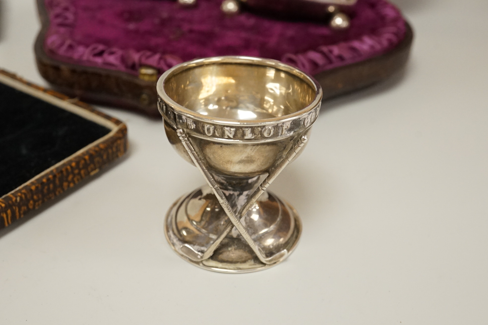 A cased pair of Victorian silver circular salts, by Edward Hutton, London, 1886, lacking spoons, together with a cased set of six silver bean end coffee spoons, a cased silver spoon, a small silver 'Dunlop Golf Ball Hole